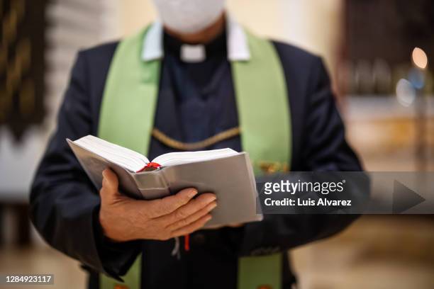 priest reading bible during congregation in church - predikant stockfoto's en -beelden