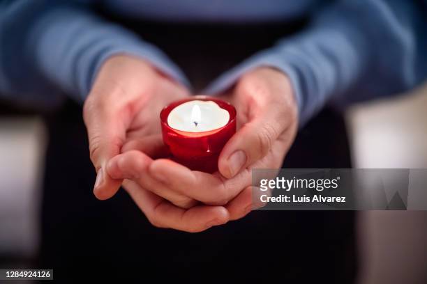 close-up of woman holding a votive candle - tod stock-fotos und bilder