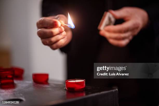 lighting up a votive candle in church - capilla interior fotografías e imágenes de stock