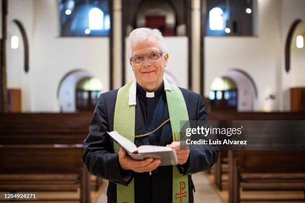 portrait of a priest in church reading the bible - cross religion stock-fotos und bilder