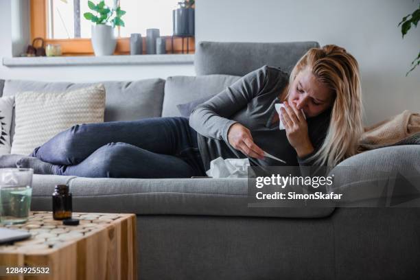 sick woman with thermometer lying on the couch at home - vomit stock pictures, royalty-free photos & images