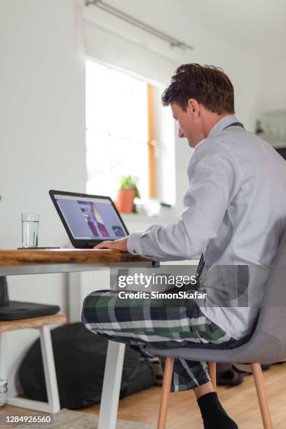 businessman in quarantine having a video conference on his laptop at home - simon nerd stock pictures, royalty-free photos & images