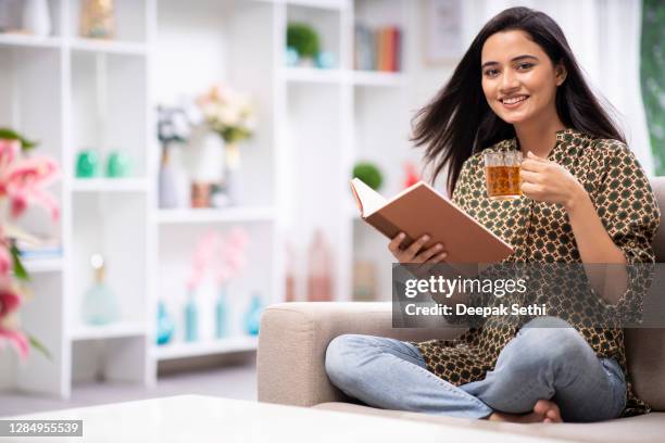 mujer en casa sofá sentado - foto de stock - herbal tea fotografías e imágenes de stock