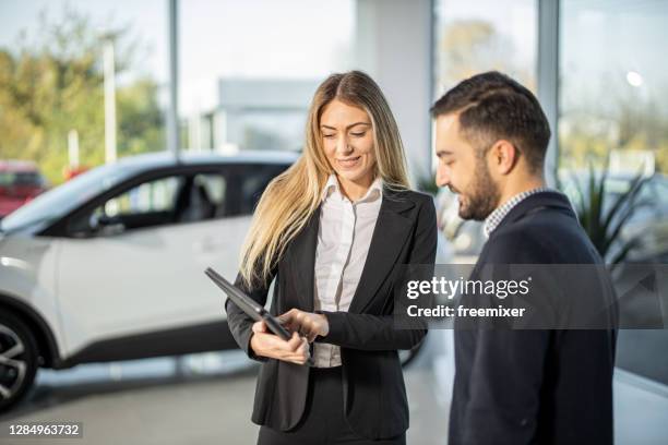 de verkoopster die van de auto aan mannelijke prestaties van de klantenauto op tablet toont - car salesman stockfoto's en -beelden