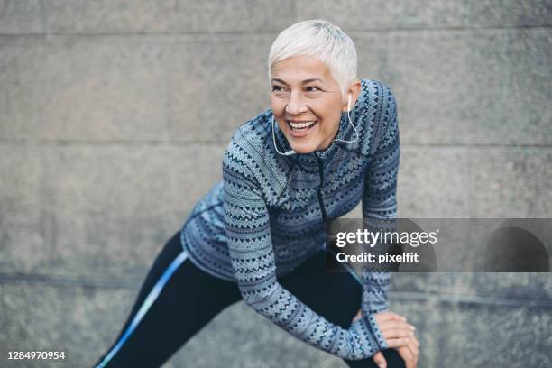 mujer madura en ropa deportiva que se extiende fuera - fitness or vitality or sport and women fotografías e imágenes de stock