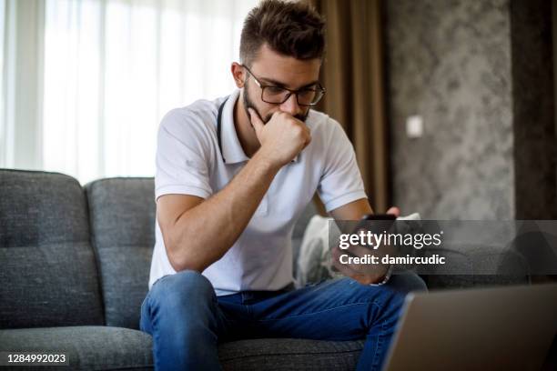 joven preocupado trabajando en casa - worried fotografías e imágenes de stock