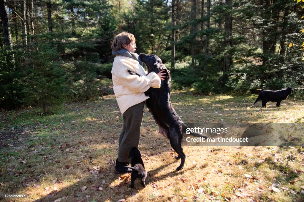 Young woman with purebred flat-coated retriever mother and puppy.