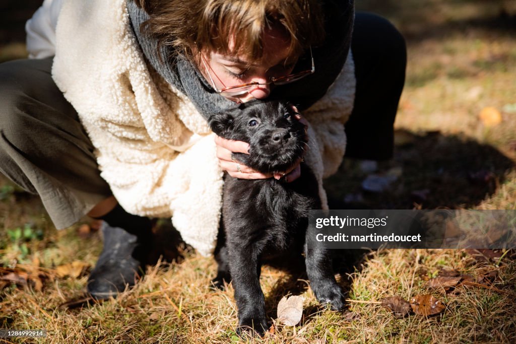 Joven mujer besando pura raza plana recubierta retriever cachorro.