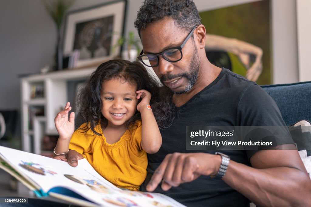 深情的父親看書與可愛的混合種族女兒
