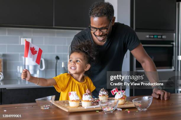 father and daughter decorate cupcakes while celebrating canada day at home - bandeira do canadá imagens e fotografias de stock