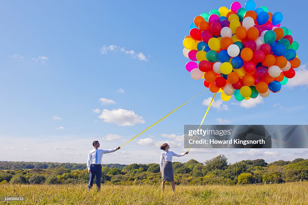 Business couple holding bunch of balloons