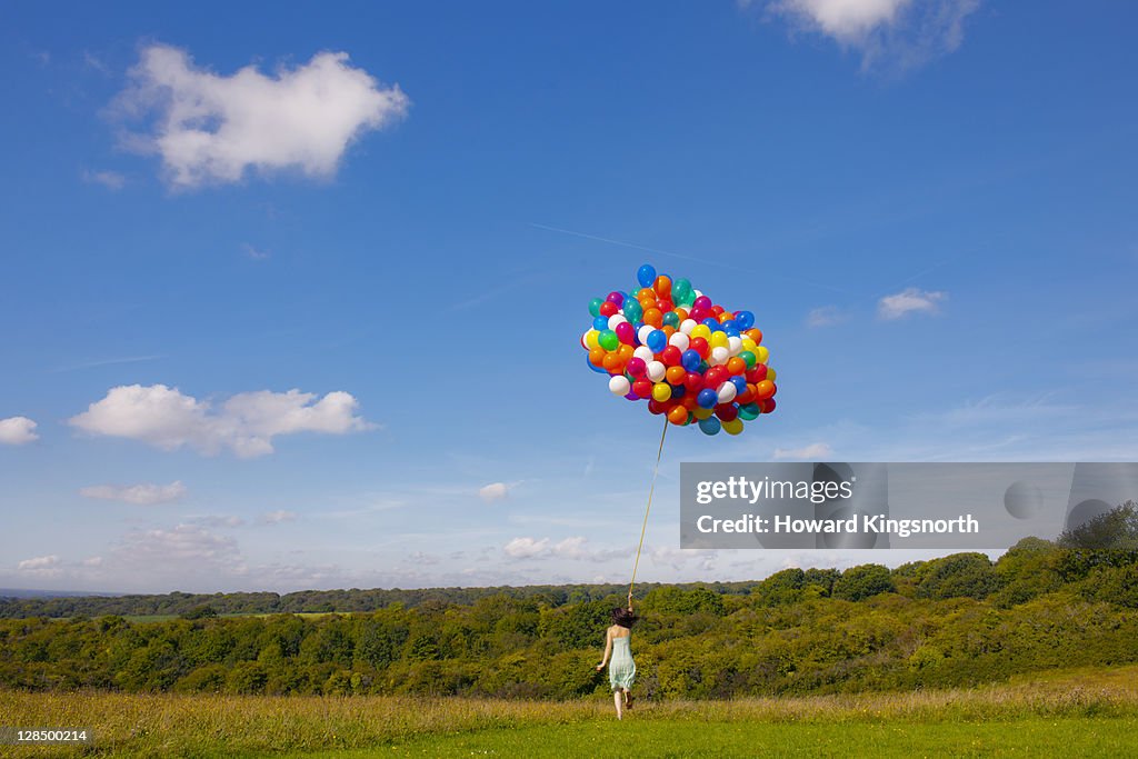Woman running holding big bunch of balloons