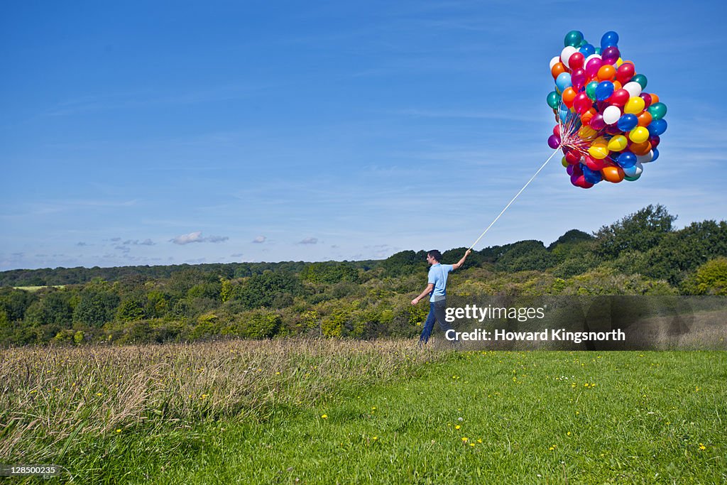 Man walking with big bunch of balloons