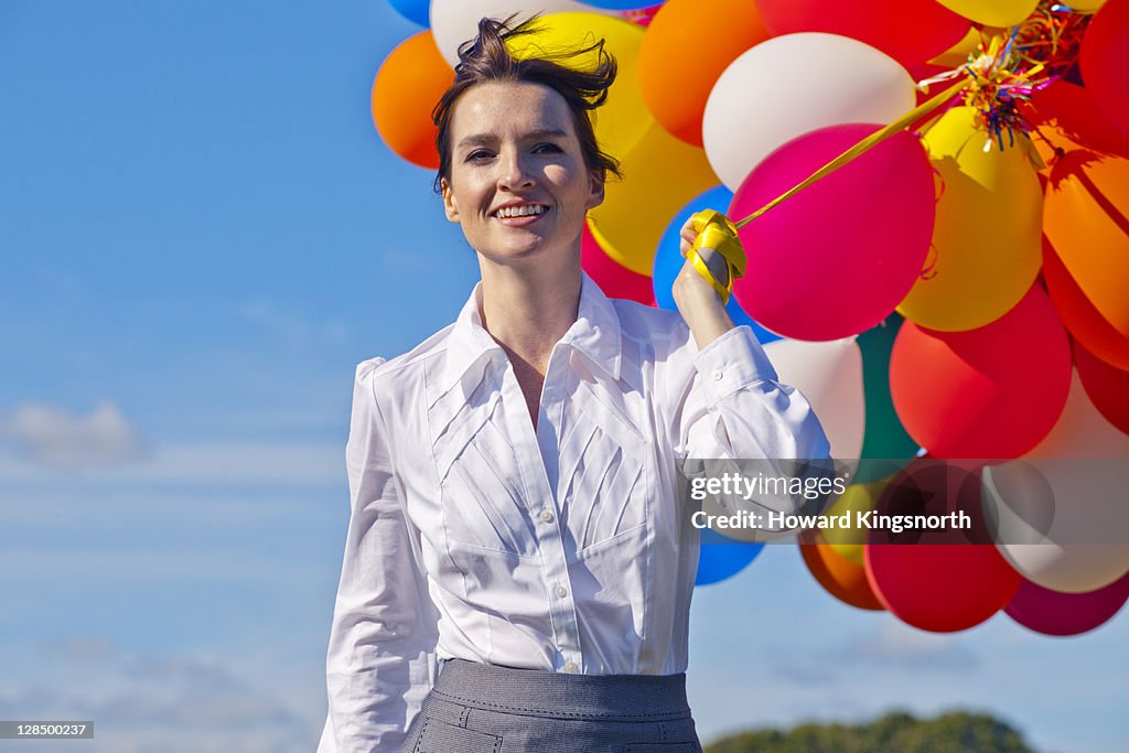 Businesswoman holding bunch of balloons