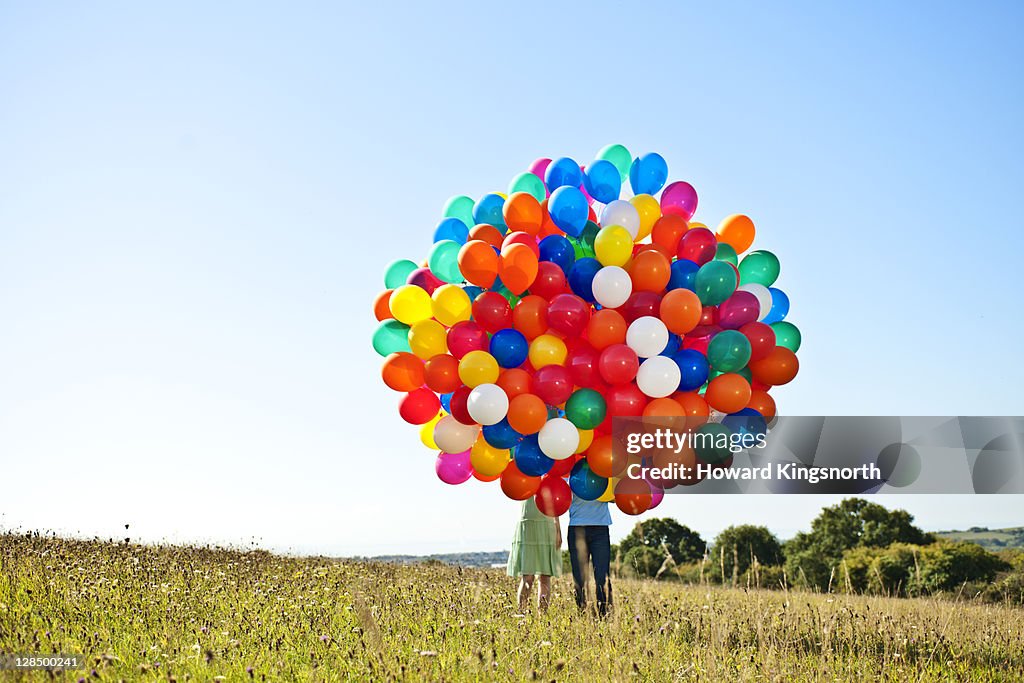 Couple holding big bunch of balloons