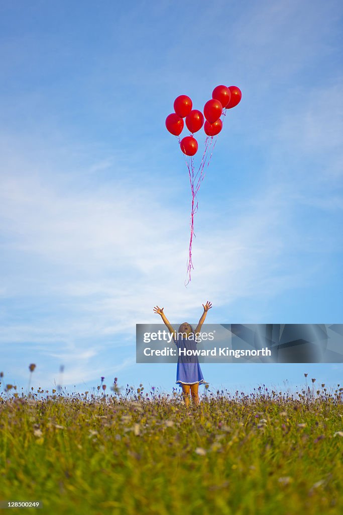 Female child releasing bunch of red balloons
