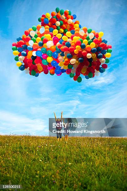 2 children releasing balloons - balloons in sky stock pictures, royalty-free photos & images