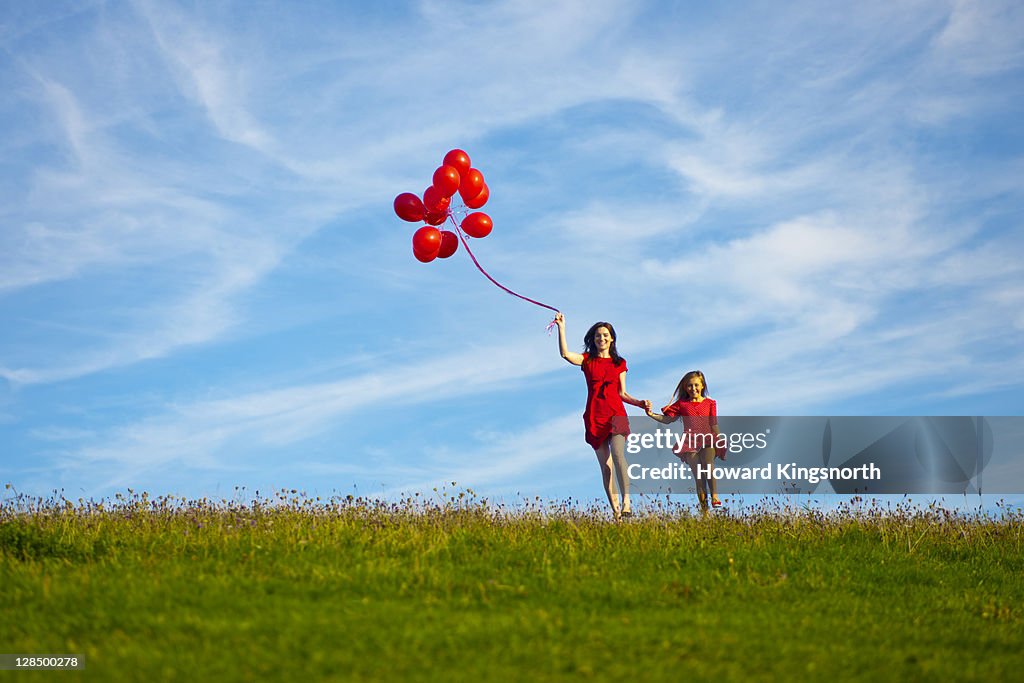 Mother and child holding red balloons