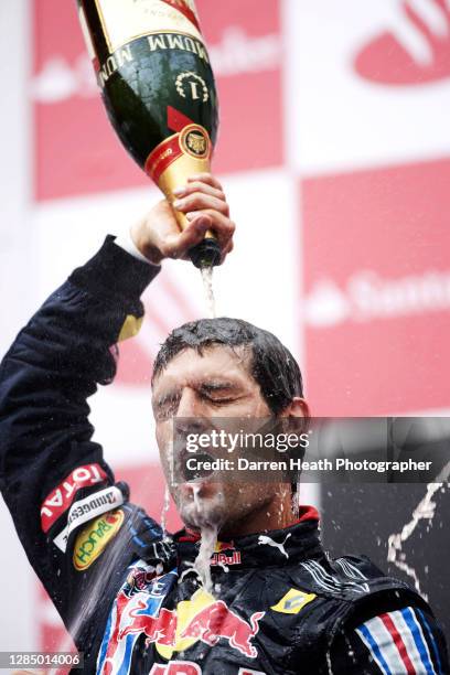 Australian Red Bull Racing Formula One driver Mark Webber celebrates by spraying, pouring and drinking champagne on the winners podium after winning...