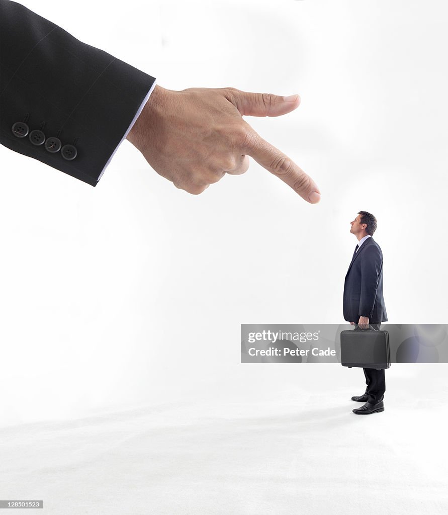 Giant hand pointing at male executive