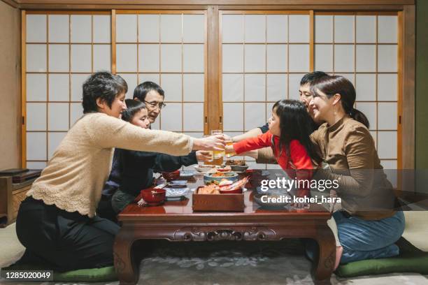 japanische mulit generation familie trinken einen toast vor dem essen osechi ryori, japanische neujahrsgerichte, auf dem esstisch in japanischen zimmer - osechi ryori stock-fotos und bilder