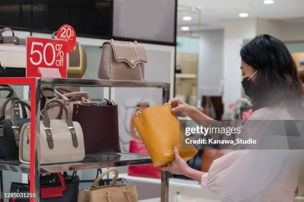 chinese vrouw die een leerhandtas op verkoop controleert - outlet stockfoto's en -beelden