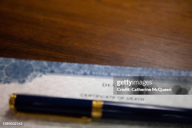 death certificate on wooden desk under pen - coroner stock-fotos und bilder