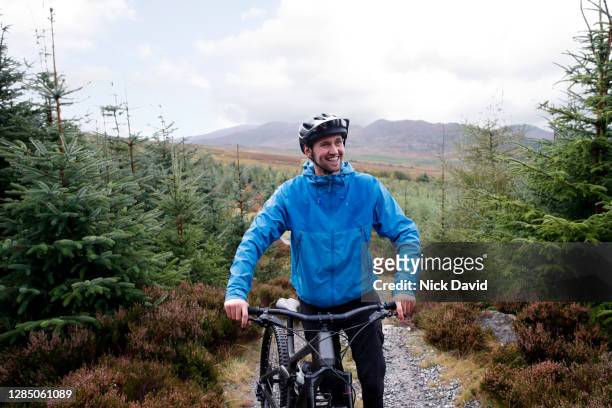 a portrait of a happy male mountain biker standing next to his bike - confidence male landscape stock-fotos und bilder