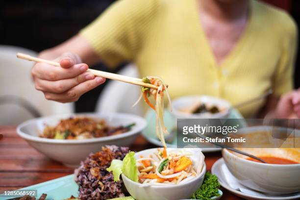 vrouw die som tam groene papajasalade en thais voedsel heeft - thaïse gerechten stockfoto's en -beelden