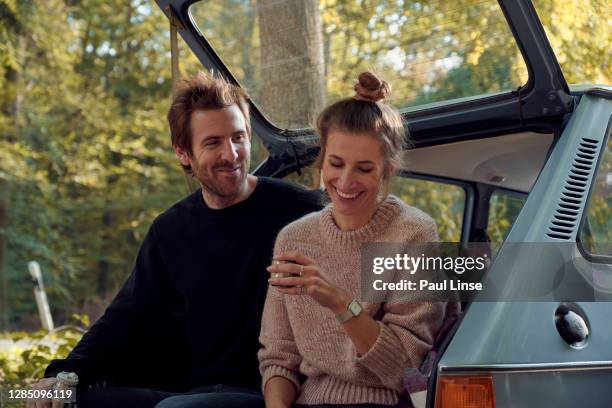 young couple sitting in trunk of their car drinking tea and having fun. - tea outdoor stock-fotos und bilder