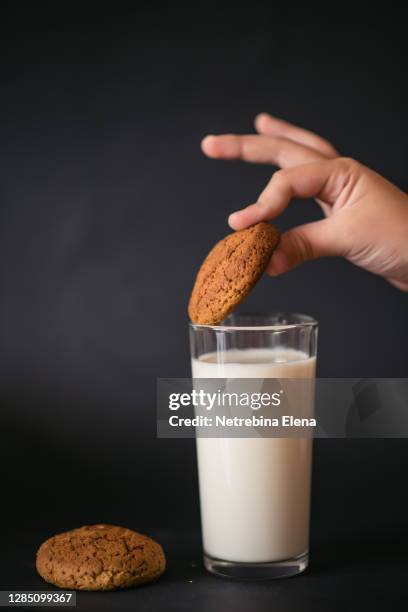 a glass of milk with oatmeal gingerbread on a black background - vache noire et blanche photos et images de collection