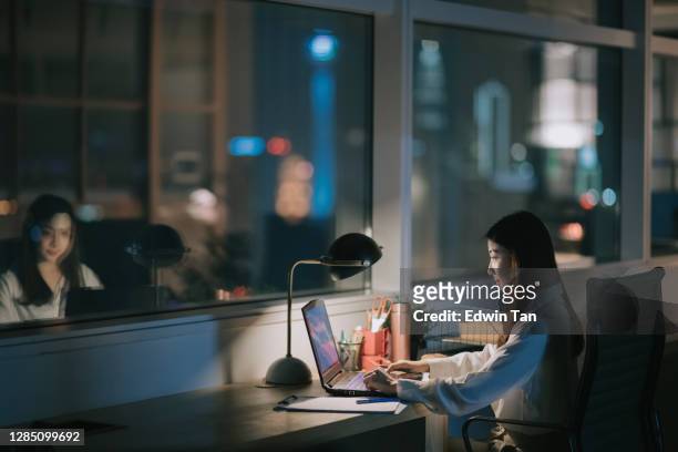 asiatische chinesische angestellte arbeiten spät im büro allein in der nacht eilen für finanzbericht - window display stock-fotos und bilder