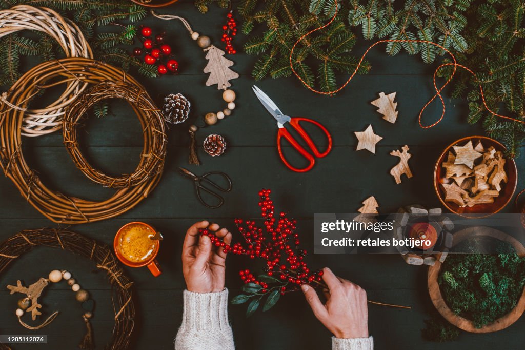 Man decorating Christmas wreath on wooden table