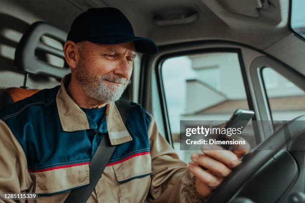 l'uomo delle consegne che usa il suo telefono e controlla gli ordini - autista mestiere foto e immagini stock