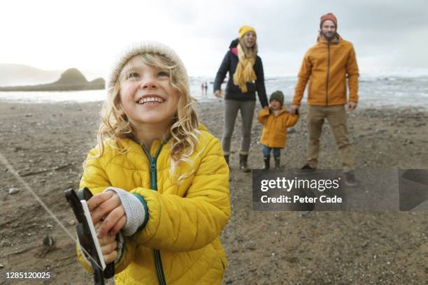 family playing with kites on beach - girl blowing sand stock-fotos und bilder