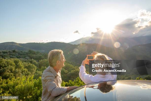 coppia matura rilassarsi contro l'auto all'alba - car top view foto e immagini stock