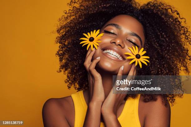 linda mulher étnica com flor amarela - fundo amarelo - fotografias e filmes do acervo
