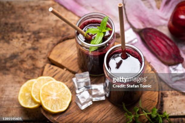 rote beete saft im glas mit eis und limettenfrüchten - beetroot juice stock-fotos und bilder