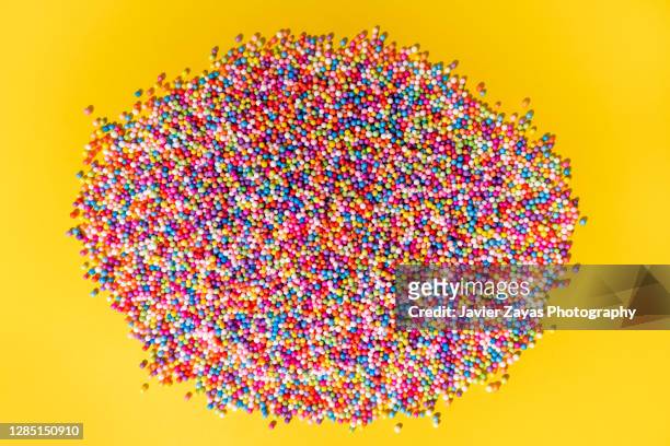 balls with vibrant colors on yellow colored background - pile of candy stock pictures, royalty-free photos & images