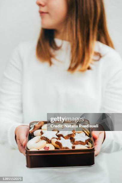 teen girl holding a tin box full of traditional swiss cookies baked in the time of advent. - natalia star stock pictures, royalty-free photos & images