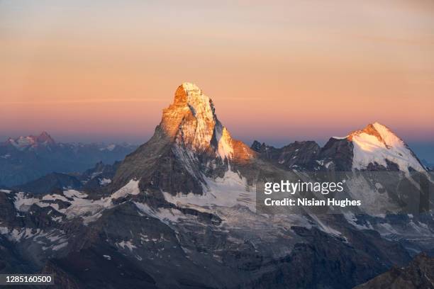aerial view of matterhorn and the snow capped peaks around it in switzerland at sunrise - vetta foto e immagini stock