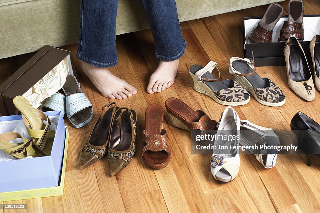 Young woman sitting on couch trying on shoes