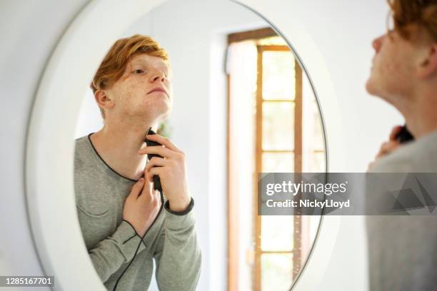 teenager shaving with an electric razor in his bathroom at home - hair clipper stock pictures, royalty-free photos & images