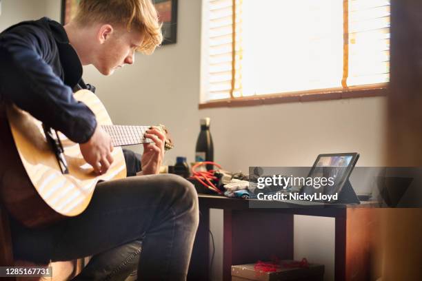 jongen die gitaar speelt tijdens een online klasse thuis - learn guitar stockfoto's en -beelden