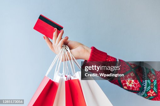 Close up crooped shot of woman hand holding many paper handbags and red credit card Close up crooped shot of woman hand holding many paper handbags and red credit card