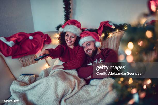 cute couple enjoying christmas with tv and movie under the blankets - christmas movie stock pictures, royalty-free photos & images