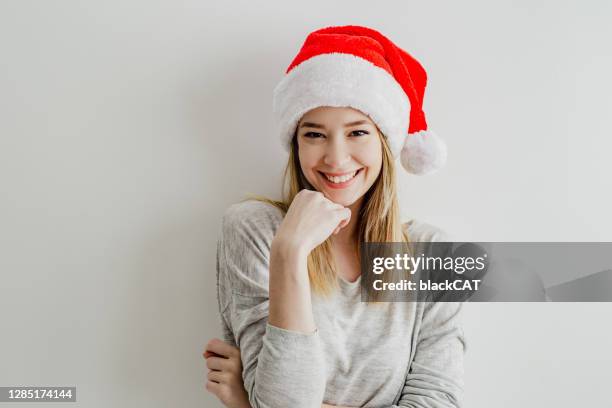 retrato de una joven frente a una pared blanca con un sombrero de papá noel - santa face fotografías e imágenes de stock