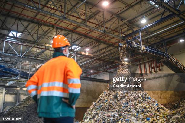 worker observing processing of waste at recycling facility - recycling center stock pictures, royalty-free photos & images