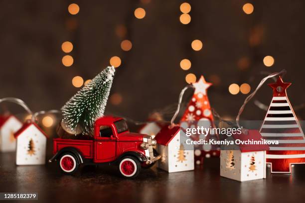 toy car carrying a christmas gift in a snowy landscape - christmas toys wooden background foto e immagini stock