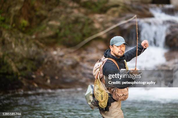 man fly fishing in a mountain river with a waterfall - man fishing stock pictures, royalty-free photos & images